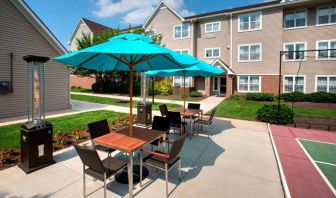 Sonesta ES Suites Allentown Bethlehem Airport’s patio is furnished with shaded tables and chairs.