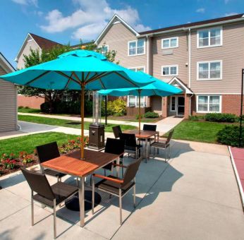 Sonesta ES Suites Allentown Bethlehem Airport’s patio is furnished with shaded tables and chairs.