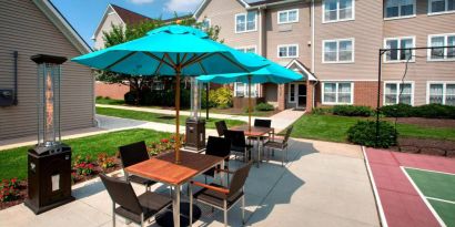 Sonesta ES Suites Allentown Bethlehem Airport’s patio is furnished with shaded tables and chairs.