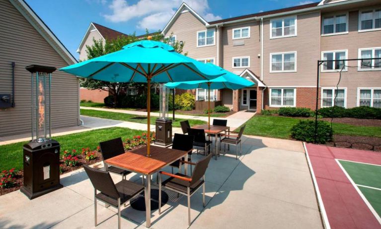 Sonesta ES Suites Allentown Bethlehem Airport’s patio is furnished with shaded tables and chairs.