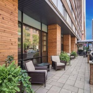 The hotel’s terrace by the entrance features armchairs, coffee tables, and potted plants.