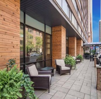 The hotel’s terrace by the entrance features armchairs, coffee tables, and potted plants.