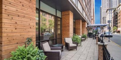 The hotel’s terrace by the entrance features armchairs, coffee tables, and potted plants.