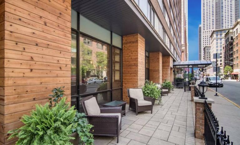 The hotel’s terrace by the entrance features armchairs, coffee tables, and potted plants.