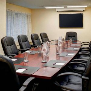 Meeting room in Sonesta ES Suites Chicago Downtown Magnificent Mile - Medical, with long wooden table, black leather chairs, and a TV.