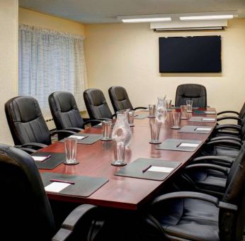 Meeting room in Sonesta ES Suites Chicago Downtown Magnificent Mile - Medical, with long wooden table, black leather chairs, and a TV.