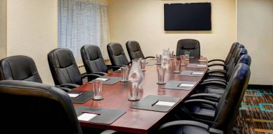 Meeting room in Sonesta ES Suites Chicago Downtown Magnificent Mile - Medical, with long wooden table, black leather chairs, and a TV.