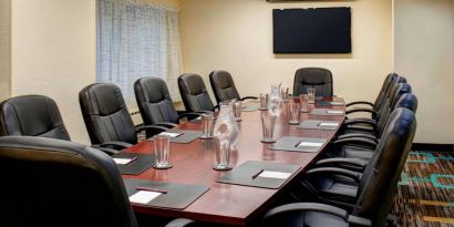 Meeting room in Sonesta ES Suites Chicago Downtown Magnificent Mile - Medical, with long wooden table, black leather chairs, and a TV.