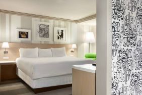 King bed guest room in Royal Sonesta Minneapolis Downtown, featuring art on the wall and a bedside armchair.