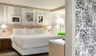 King bed guest room in Royal Sonesta Minneapolis Downtown, featuring art on the wall and a bedside armchair.