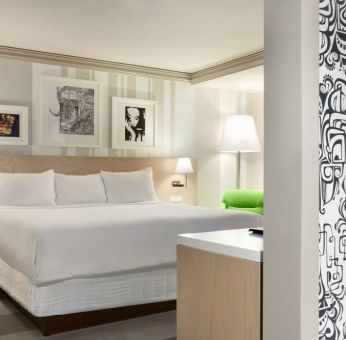 King bed guest room in Royal Sonesta Minneapolis Downtown, featuring art on the wall and a bedside armchair.