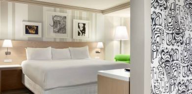 King bed guest room in Royal Sonesta Minneapolis Downtown, featuring art on the wall and a bedside armchair.