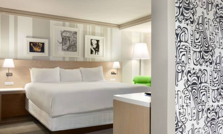 King bed guest room in Royal Sonesta Minneapolis Downtown, featuring art on the wall and a bedside armchair.