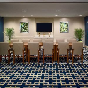 Hotel meeting room, decorated with potted plants and wall art, and featuring a dozen chairs around a long table.