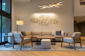 Sonesta Silicon Valley’s lobby is furnished with a comfortable sitting area, with long sofa, chairs, and multiple coffee tables.