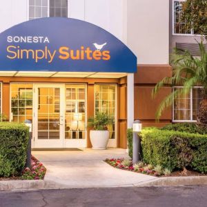 Sonesta Simply Suites Irvine East Foothill’s exterior features a covered entranceway, clear signage, and pleasant greenery.