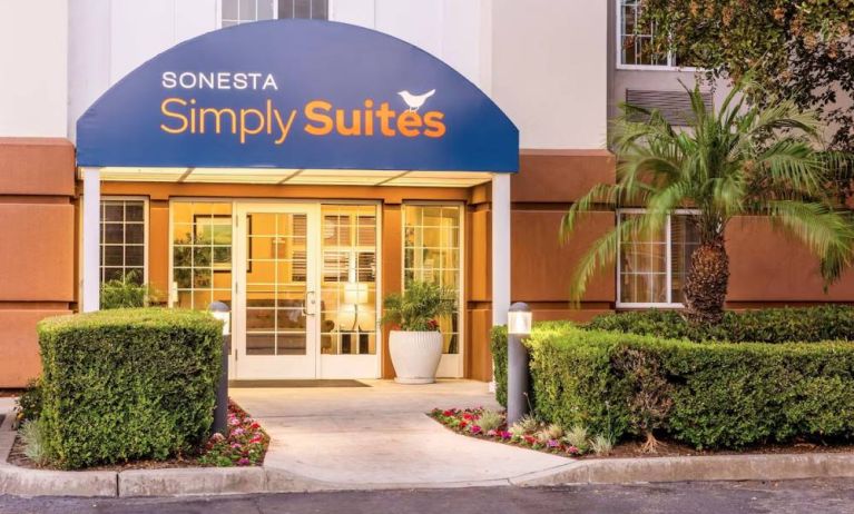 Sonesta Simply Suites Irvine East Foothill’s exterior features a covered entranceway, clear signage, and pleasant greenery.