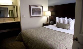 Double bed guest room in Sonesta ES Suites San Jose Airport, with bedside lamp and ensuite bathroom.