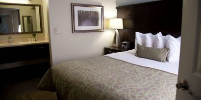 Double bed guest room in Sonesta ES Suites San Jose Airport, with bedside lamp and ensuite bathroom.