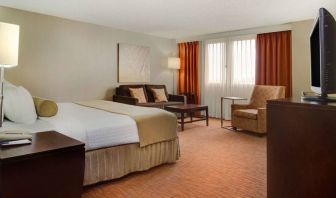 Sonesta Miami Airport double bed guest room, furnished with armchair, sofa, and window.