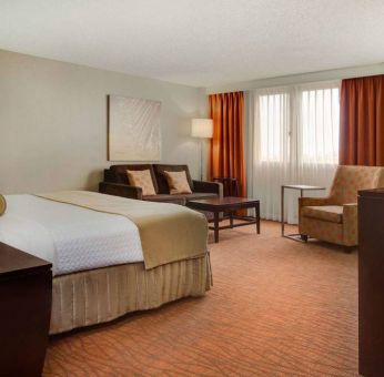 Sonesta Miami Airport double bed guest room, furnished with armchair, sofa, and window.