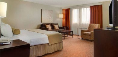 Sonesta Miami Airport double bed guest room, furnished with armchair, sofa, and window.