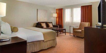 Sonesta Miami Airport double bed guest room, furnished with armchair, sofa, and window.