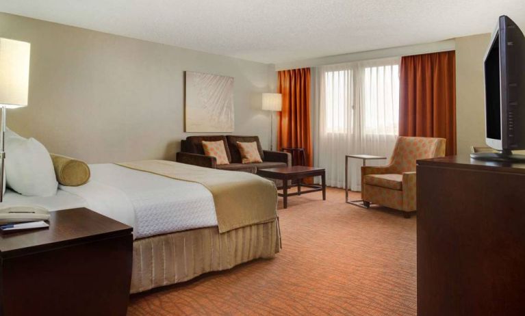 Sonesta Miami Airport double bed guest room, furnished with armchair, sofa, and window.