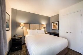 Sonesta Simply Suites Arlington double bed guest room, furnished with bedside cabinets and art on the walls.