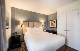 Sonesta Simply Suites Arlington double bed guest room, furnished with bedside cabinets and art on the walls.