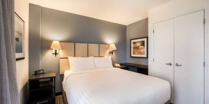 Sonesta Simply Suites Arlington double bed guest room, furnished with bedside cabinets and art on the walls.