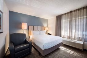 Double bed guest room in Sonesta Simply Suites Cleveland North Olmsted Airport, including armchair and windows.