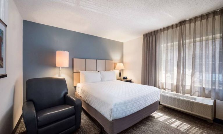 Double bed guest room in Sonesta Simply Suites Cleveland North Olmsted Airport, including armchair and windows.