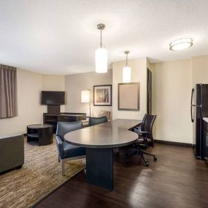 Sonesta Simply Suites Nashville Brentwood guest room workspace, featuring desk and multiple chairs, with TV and kitchenette close at hand.