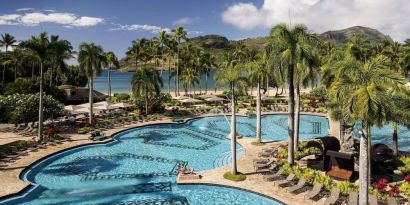 The hotel’s outdoor pool includes sun loungers and tall trees nearby.