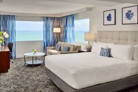 Sonesta Fort Lauderdale Beach double bed guest room, featuring ocean views, a sofa, coffee table, and workspace.