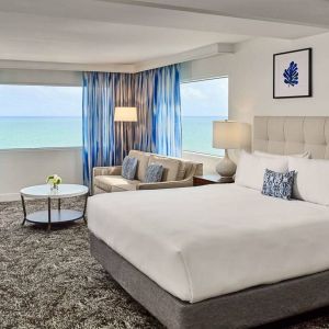 Sonesta Fort Lauderdale Beach double bed guest room, featuring ocean views, a sofa, coffee table, and workspace.