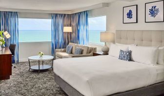 Sonesta Fort Lauderdale Beach double bed guest room, featuring ocean views, a sofa, coffee table, and workspace.