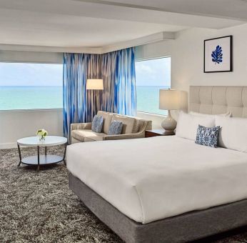 Sonesta Fort Lauderdale Beach double bed guest room, featuring ocean views, a sofa, coffee table, and workspace.