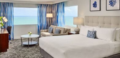 Sonesta Fort Lauderdale Beach double bed guest room, featuring ocean views, a sofa, coffee table, and workspace.