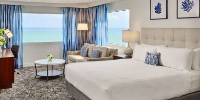 Sonesta Fort Lauderdale Beach double bed guest room, featuring ocean views, a sofa, coffee table, and workspace.