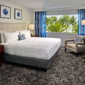 Double bed guest room in Sonesta Fort Lauderdale Beach, furnished with armchair plus workspace desk and chair.