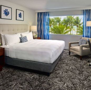 Double bed guest room in Sonesta Fort Lauderdale Beach, furnished with armchair plus workspace desk and chair.