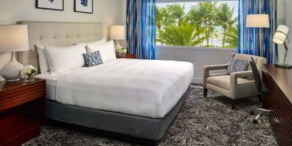 Double bed guest room in Sonesta Fort Lauderdale Beach, furnished with armchair plus workspace desk and chair.