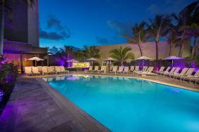 Sonesta Fort Lauderdale Beach’s outdoor pool has palm trees and sun loungers by the side, with shade available.