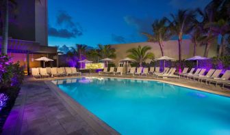 Sonesta Fort Lauderdale Beach’s outdoor pool has palm trees and sun loungers by the side, with shade available.