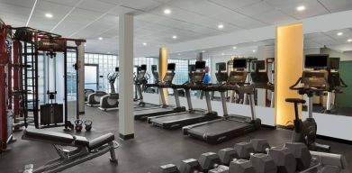 The hotel fitness center has rows of free weights, both dumbbells and kettlebells, and an assortment of exercise machines.