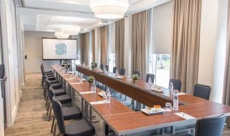 Sonesta Fort Lauderdale Beach meeting room, with a head table for one person and two long tables each with space for 10 attendees, and a projector screen.