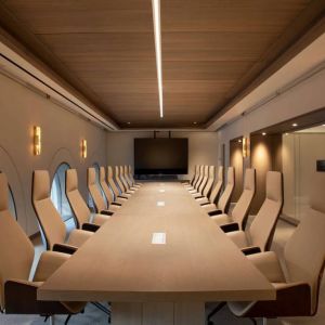 Meeting room in The Clift Royal Sonesta, featuring long table with seating for over a dozen attendees, cozy atmosphere, and large, wall-mounted TV.