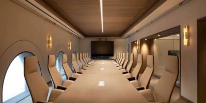 Meeting room in The Clift Royal Sonesta, featuring long table with seating for over a dozen attendees, cozy atmosphere, and large, wall-mounted TV.